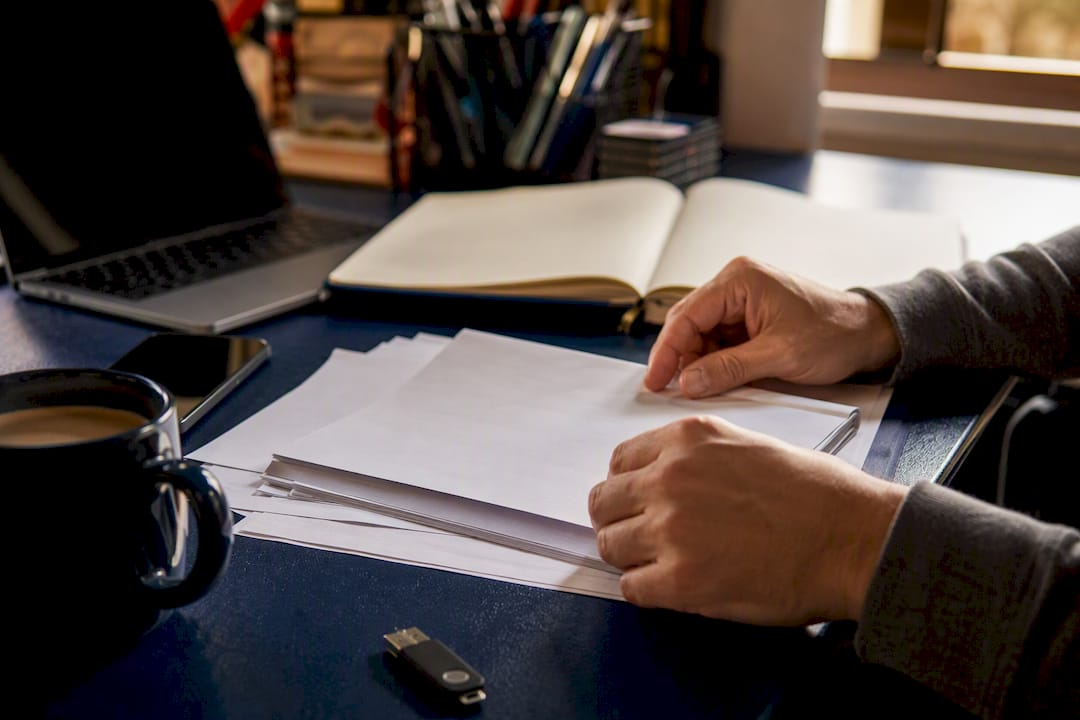 Hands preparing IRS tax forms and digital tools