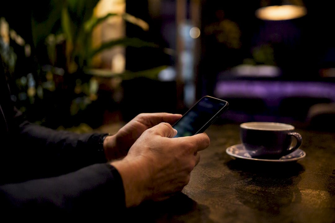 Hände verwalten Kontakte auf dem Smartphone in einem dunklen Arbeitsumfeld