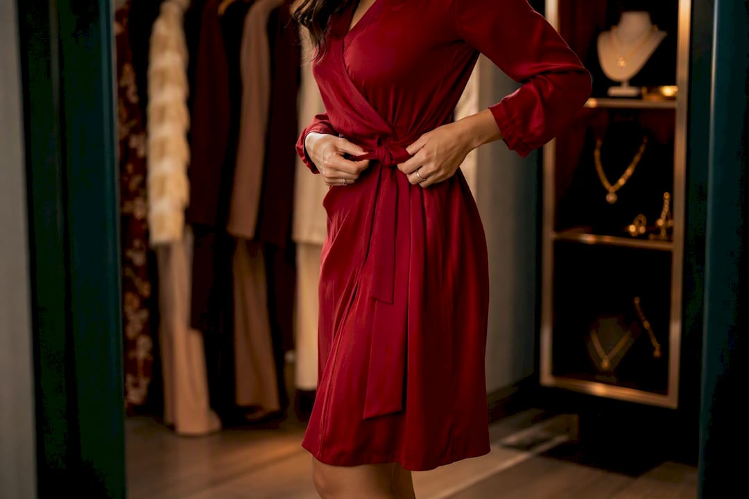 Woman adjusting wrap dress waist at fitting room