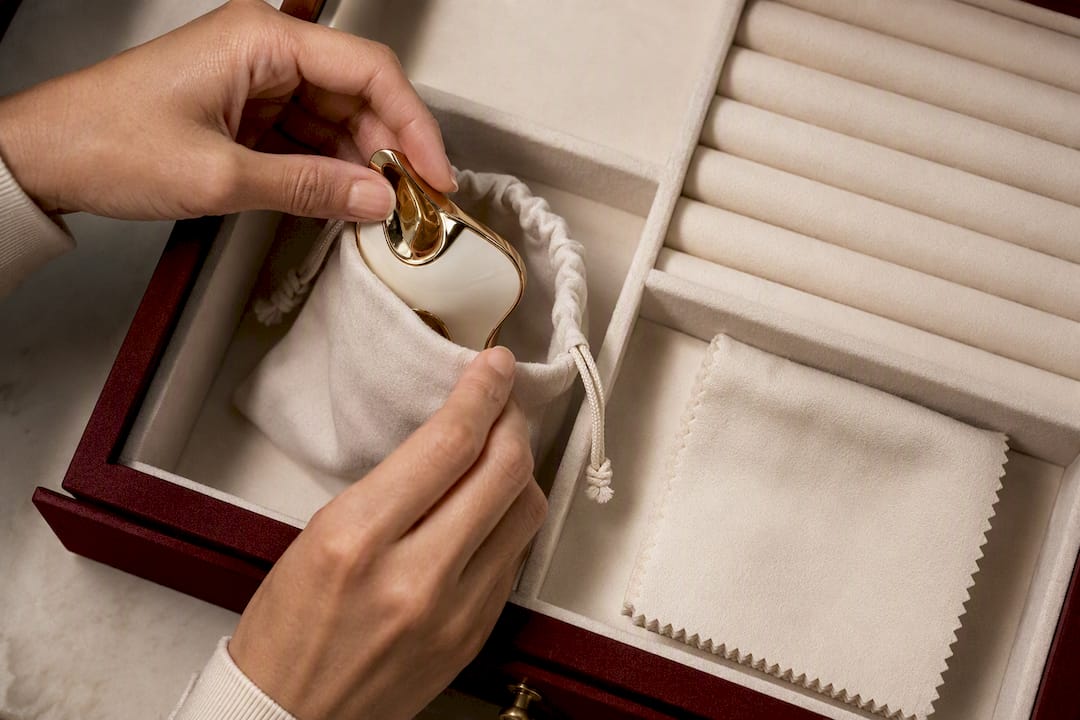 Hands storing enamel jewelry in lined pouch
