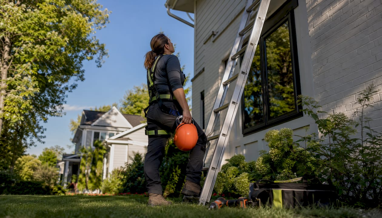 Woman inspecting ladder safety before roof access