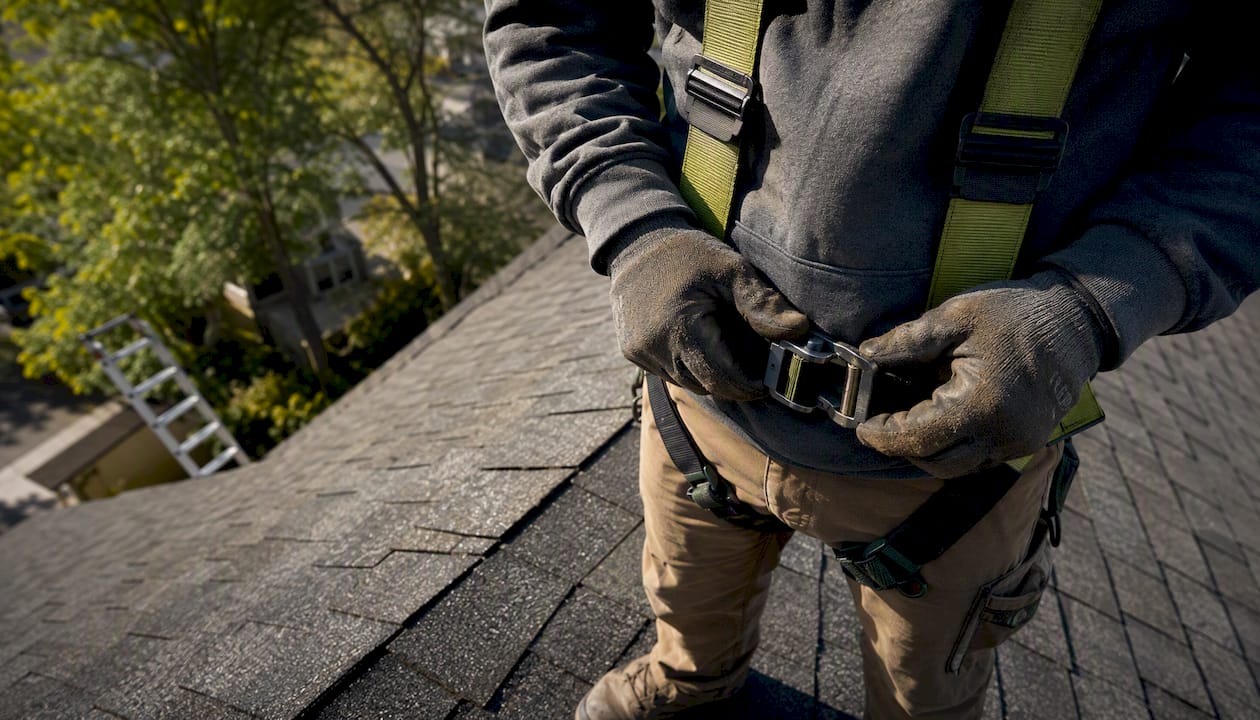 Inspector adjusting safety harness on steep roof