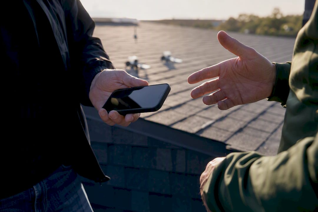 Hands exchanging smartphone on roof for coordination