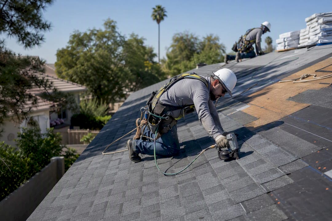Roofers installing new shingles on Phoenix home