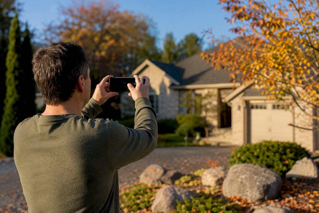 Homeowner photographing roof for damage evidence
