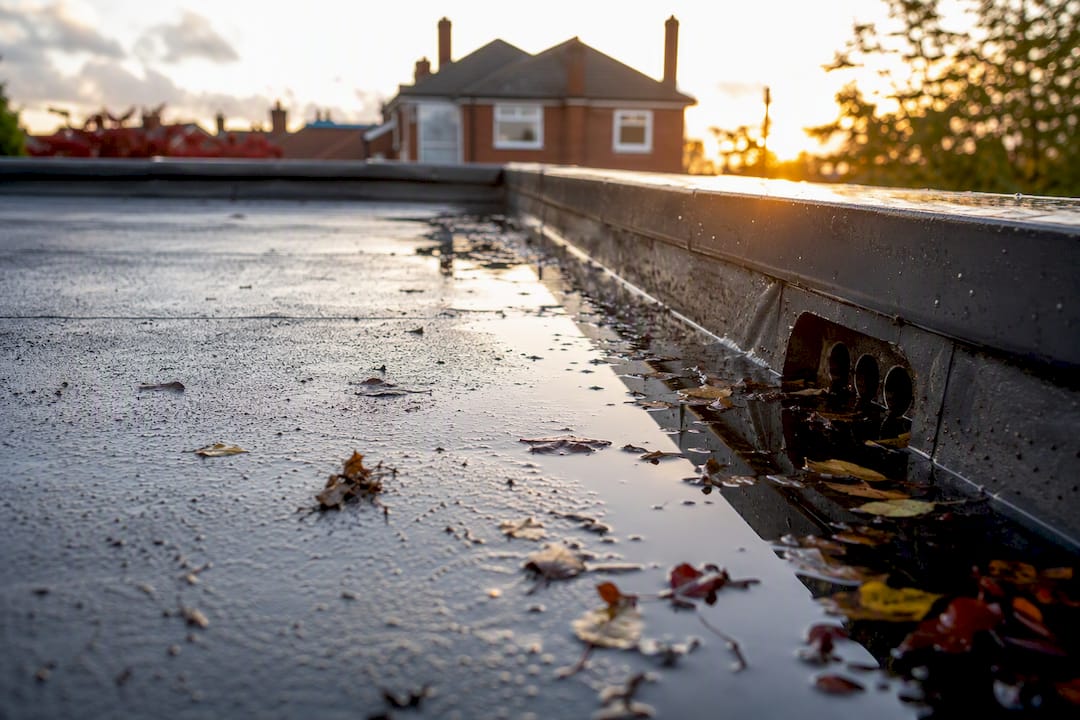 Flat roof with water ponding near drainage outlets