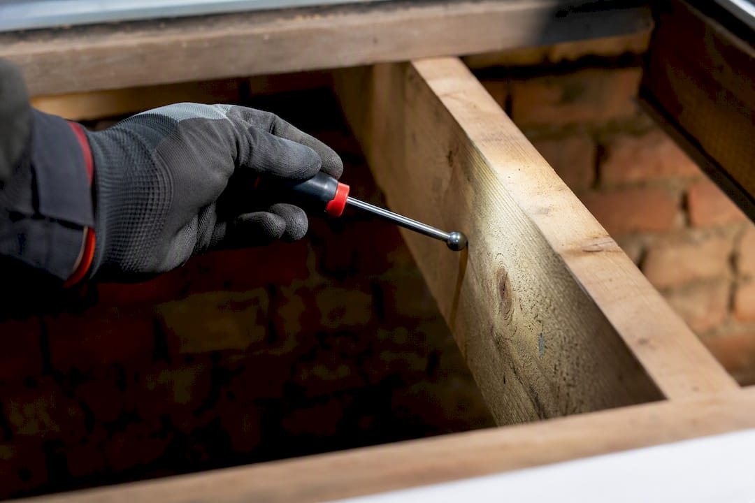 Gloved hand tapping exposed timber joist