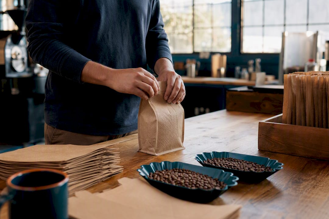 Hands packing coffee into eco-friendly bags in roastery