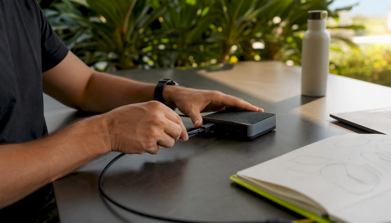 Hands plugging edge device on desk
