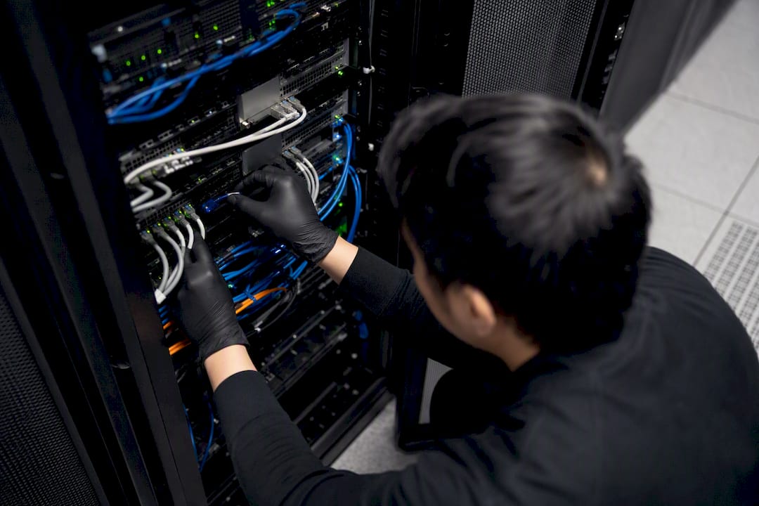 Hands connecting cables in secure server rack