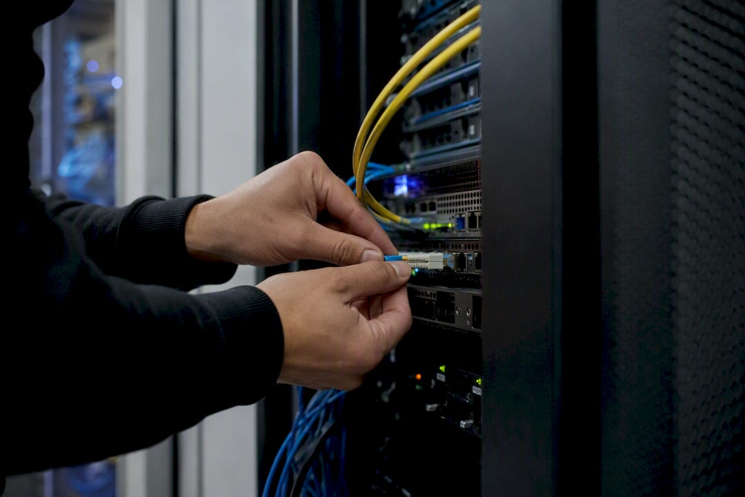 Hands connecting fiber optic cable in data center