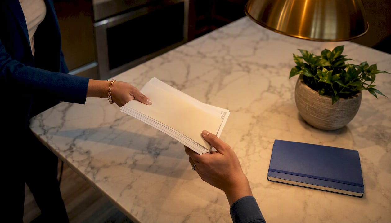 Hands exchanging land purchase documents at closing
