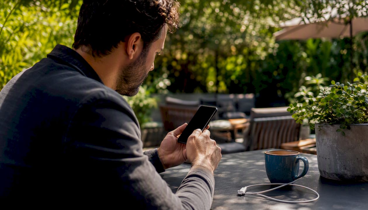 Investor's hands with smartphone and coffee cup