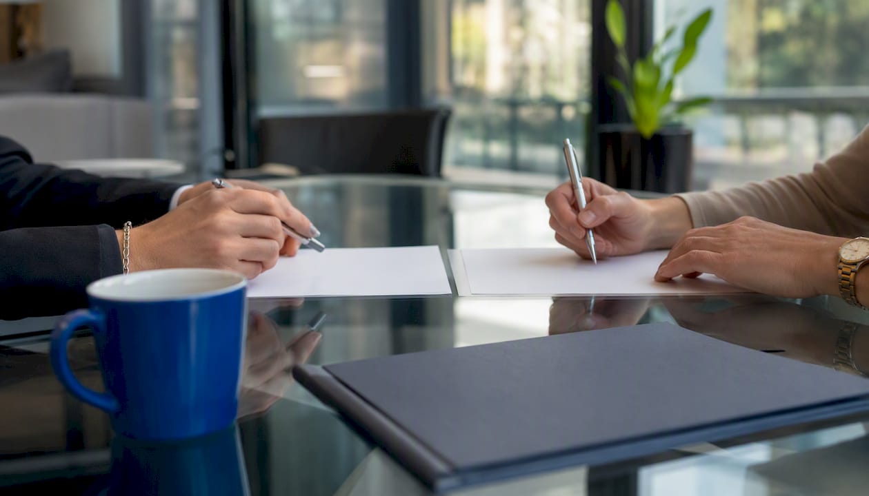 Hands exchanging real estate documents on table