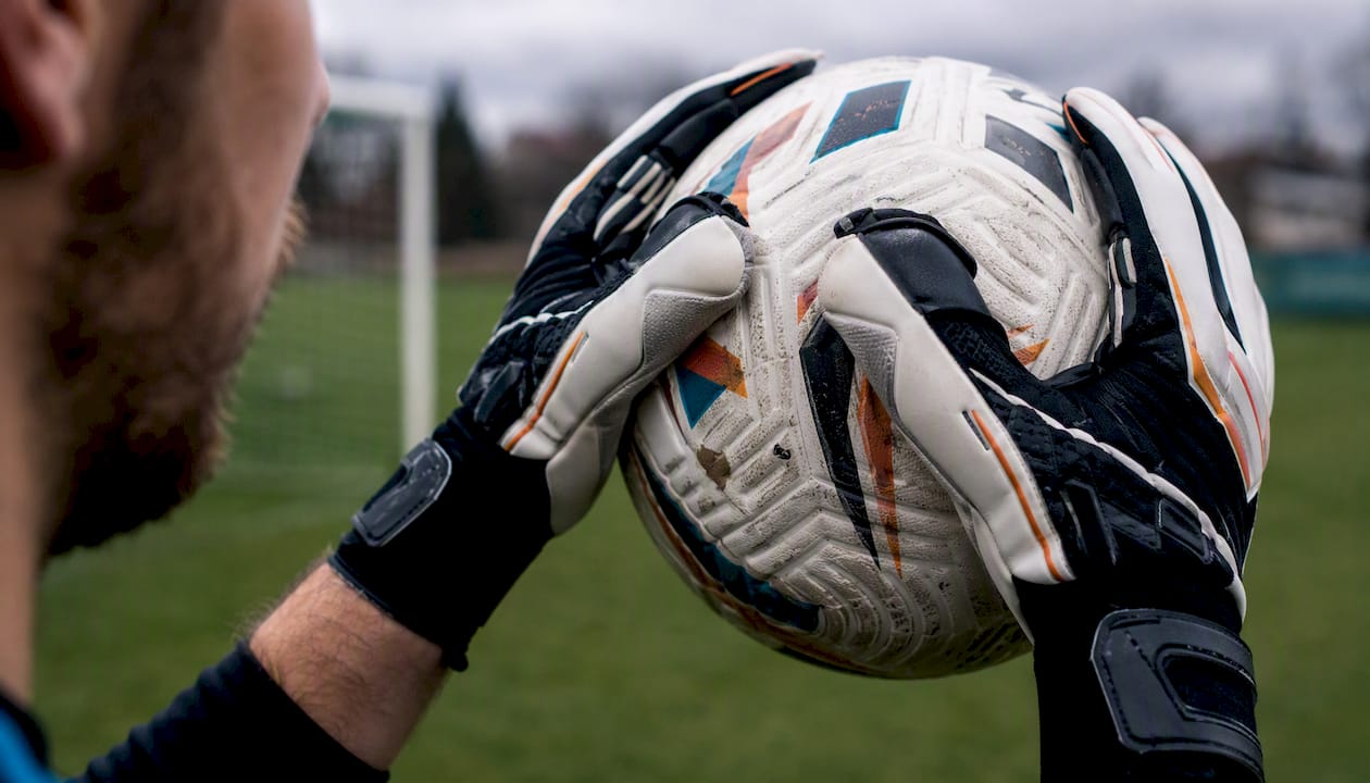 Ein Torwart fängt den Ball sicher mit seinen Rollfinger-Handschuhen.