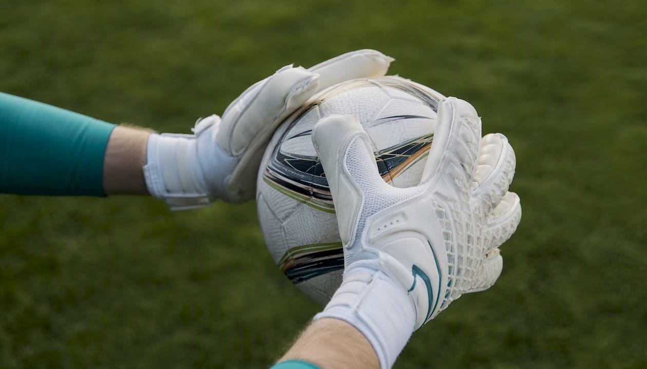 Ein Torwart hält den Ball sicher mit seinen Rollfinger-Handschuhen fest.