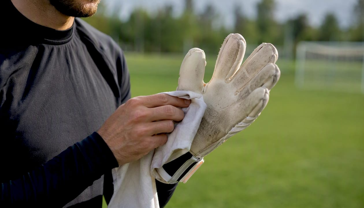 Der Torwart wischt seine Handschuhe mit einem Tuch sauber.