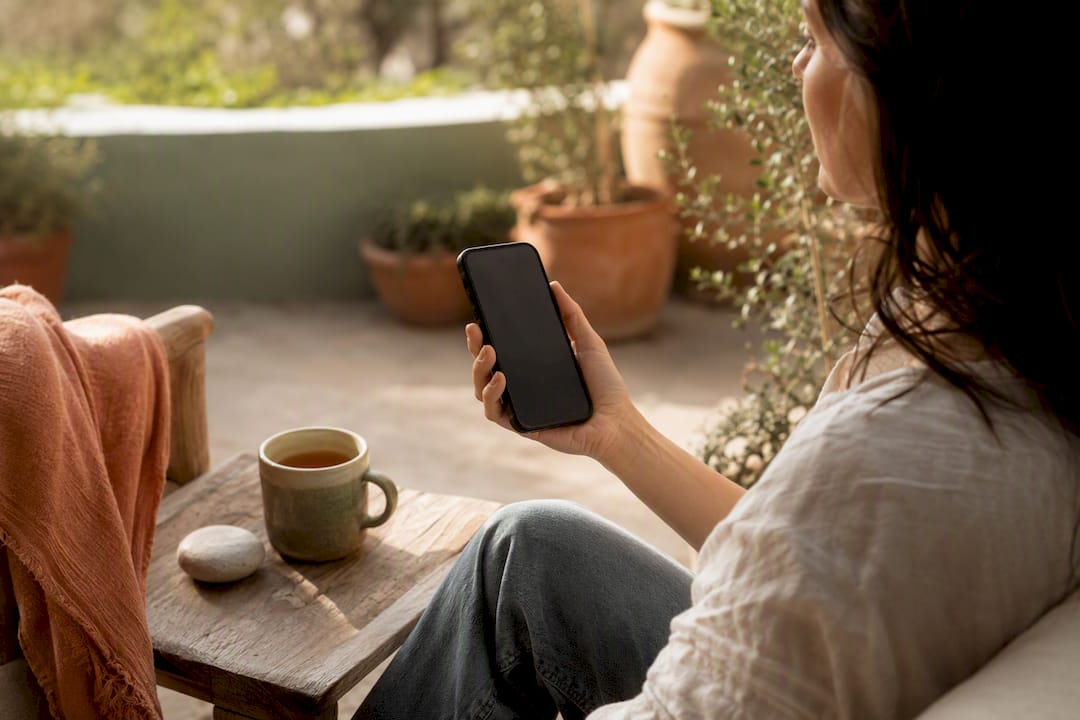 Hands holding smartphone peacefully with tea nearby
