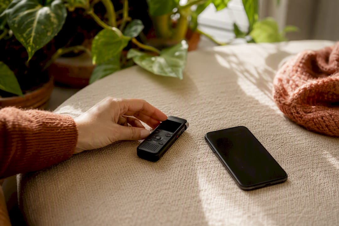 Hand pressing voice recorder near phone
