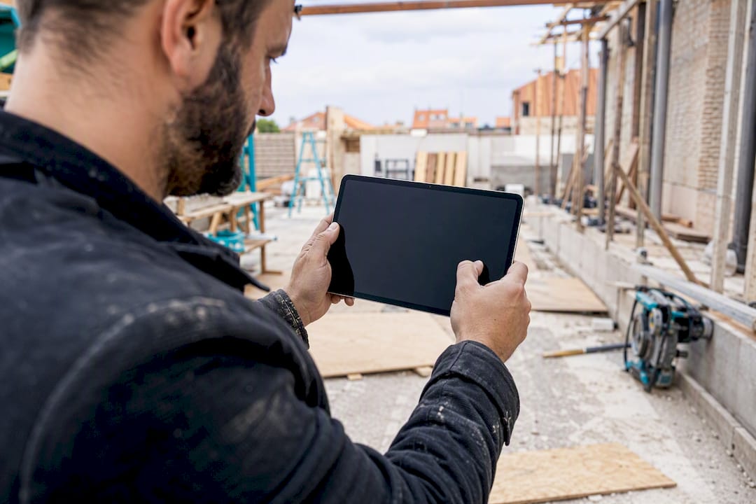 Hand macht ein Baustellenfoto mit dem Tablet