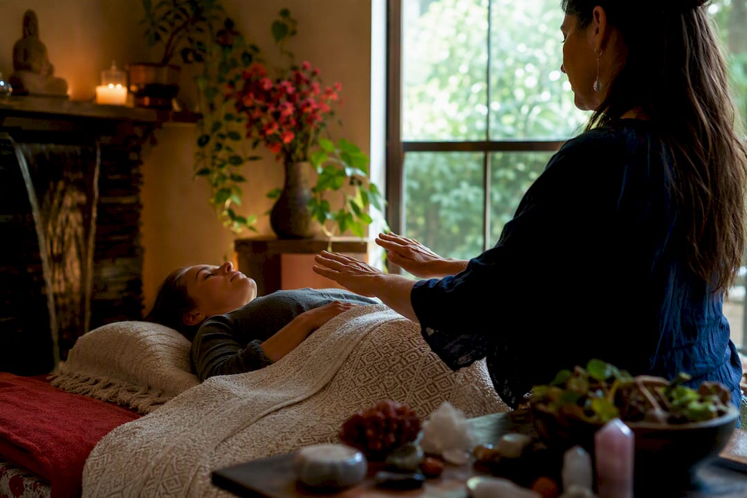 Hands performing energy healing in serene room