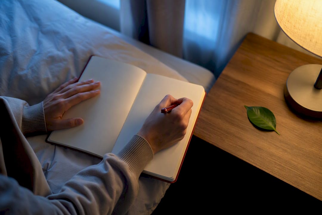 Person recording a dream in bedside journal