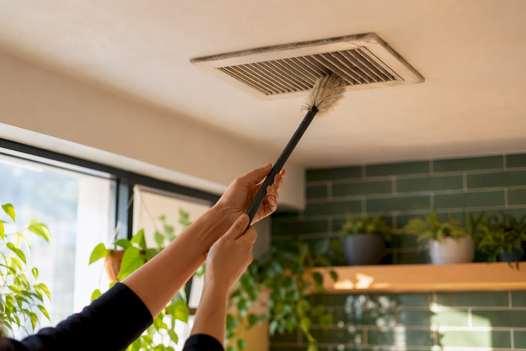 Hands cleaning ceiling vent after construction