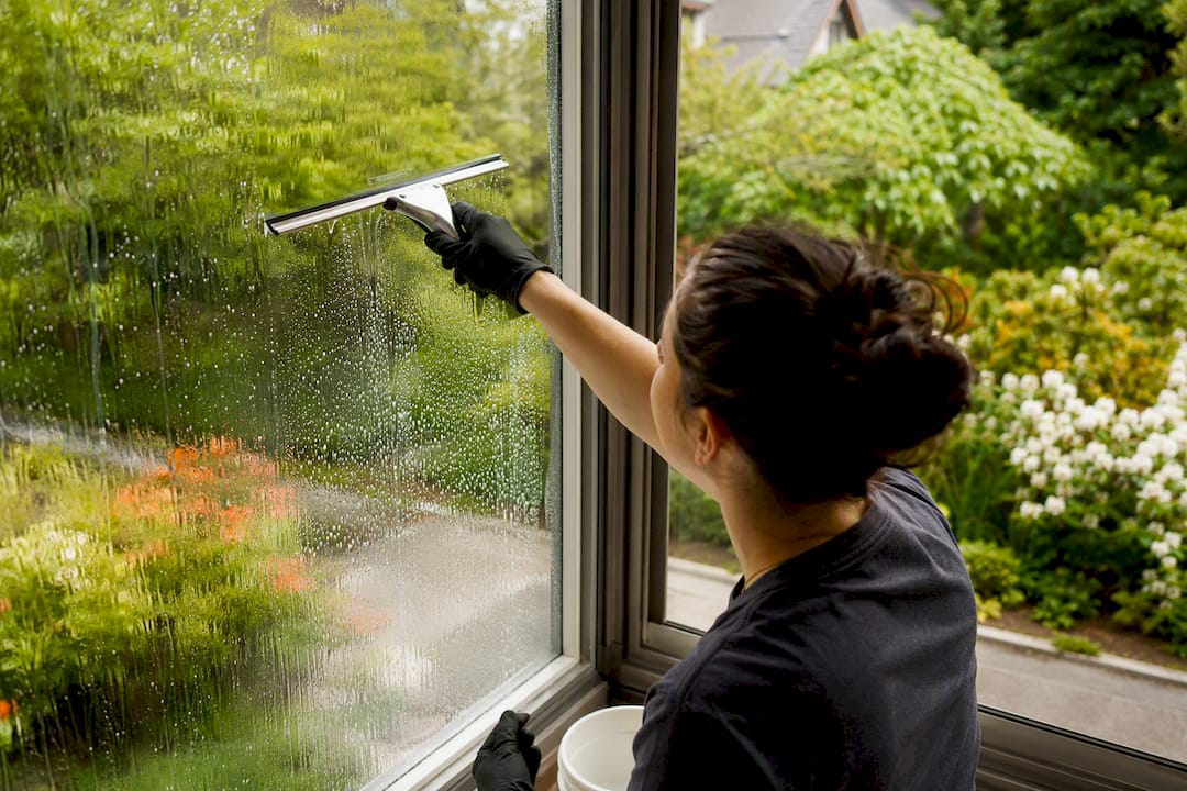 Hands cleaning window with squeegee outdoors