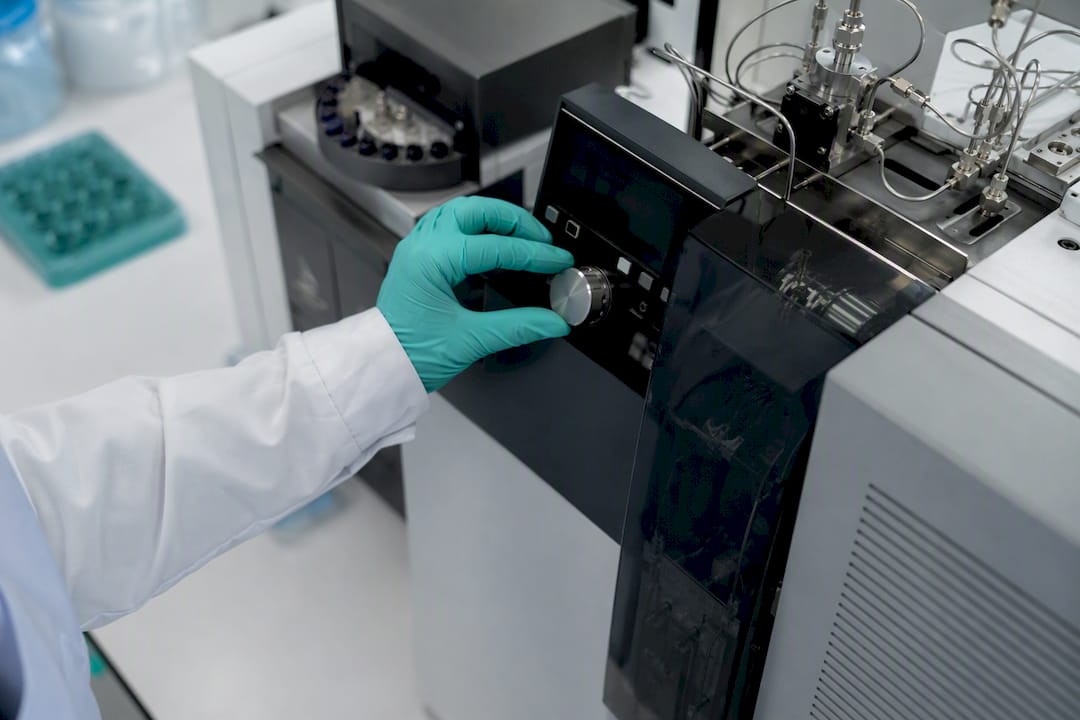 Gloved hand adjusting analytical instrument in pharma lab