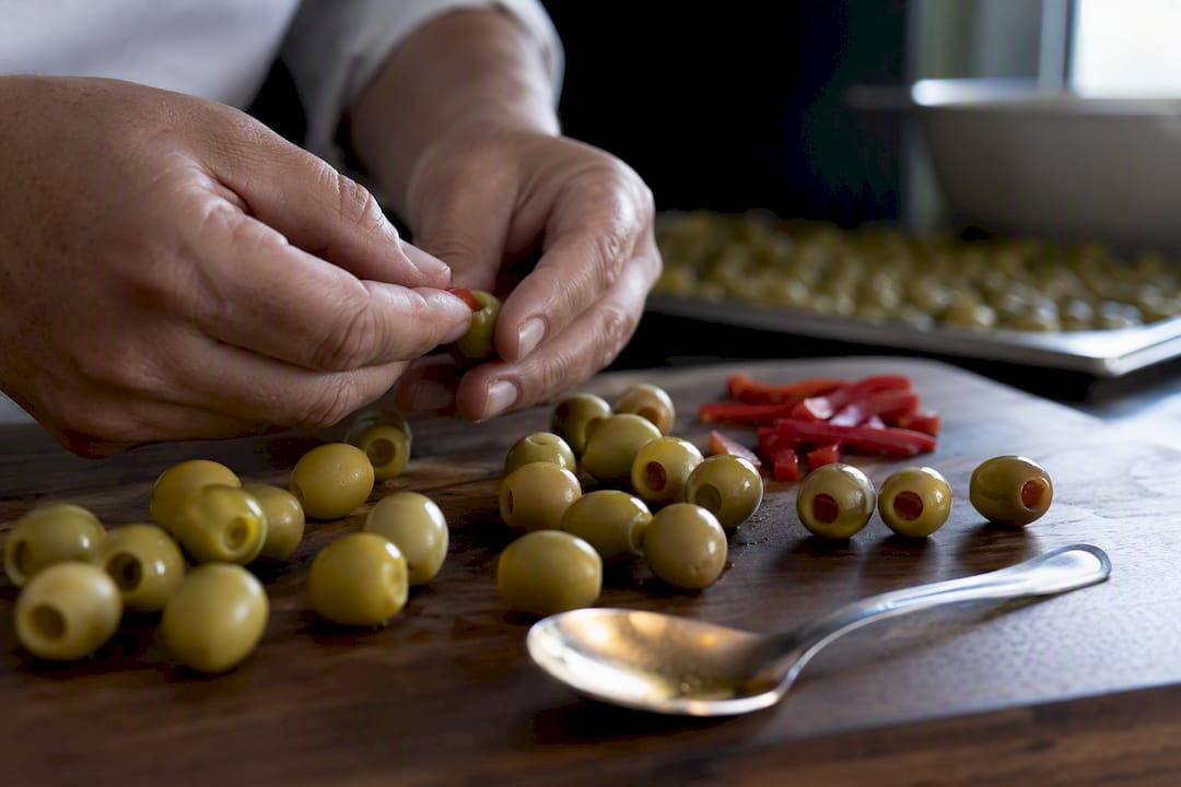 Manos rellenando aceitunas manzanilla con pimiento
