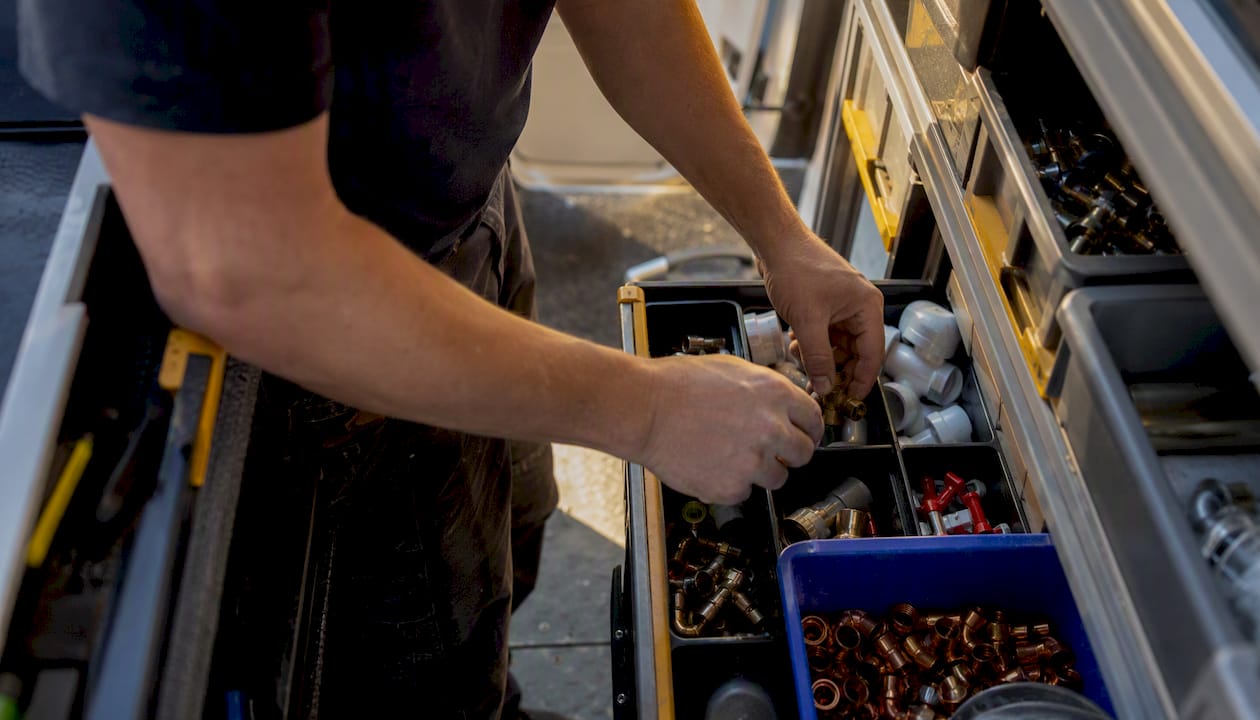Plumber hands sorting parts in van