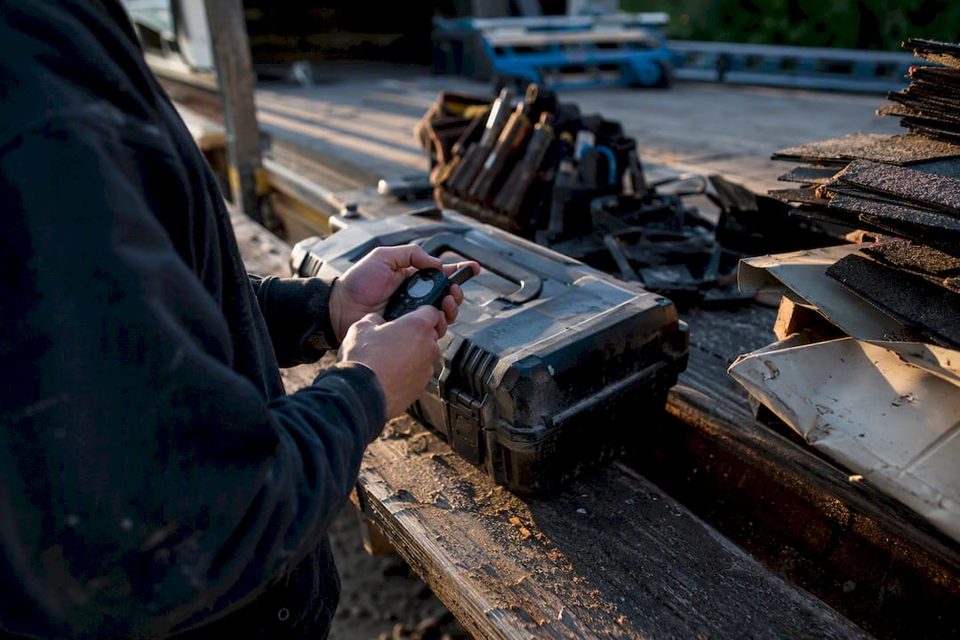 Hands adjusting stopwatch next to roofing dispatch tools