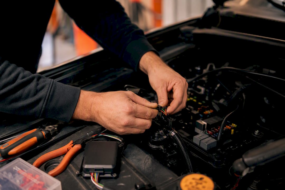 Technician wiring GPS tracker in engine bay