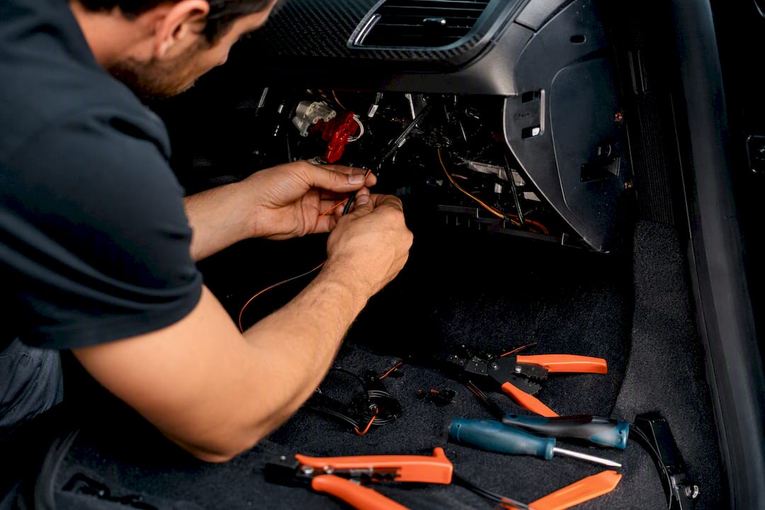Installer hands wiring tracker under dashboard