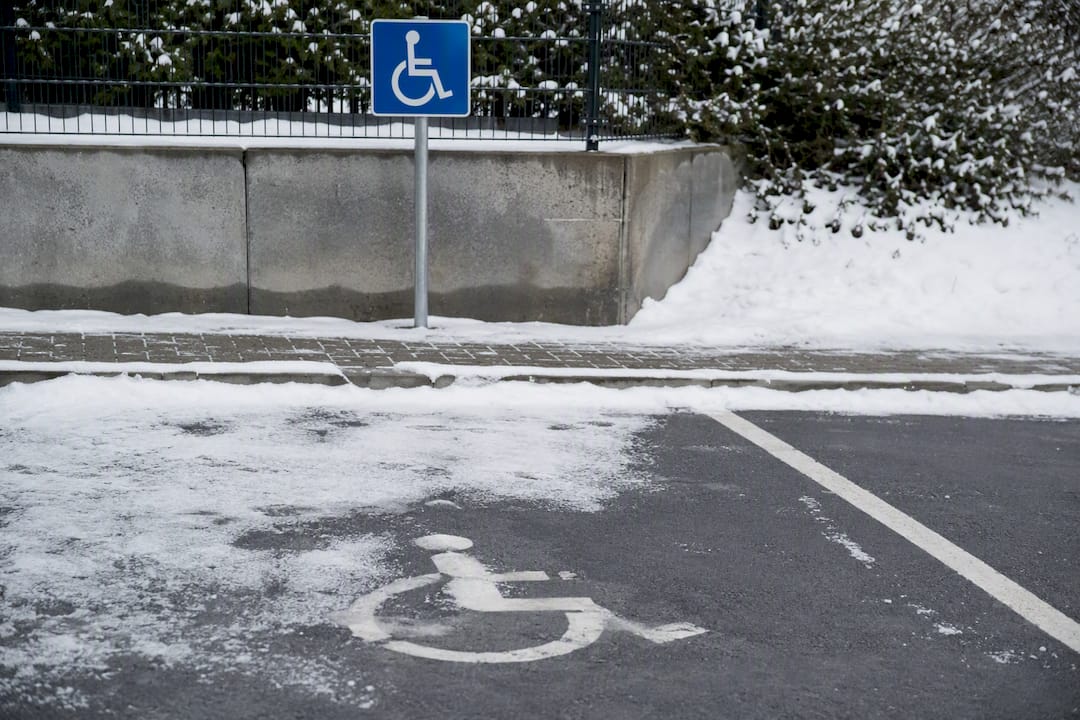 Schild für barrierefreies Parken und teilweise schneebedeckte Bodenmarkierung