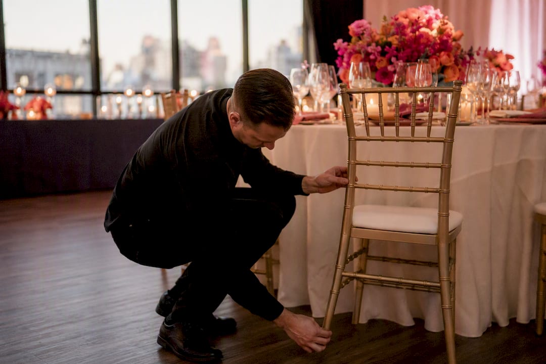 Hand testing chair leg stability at wedding venue