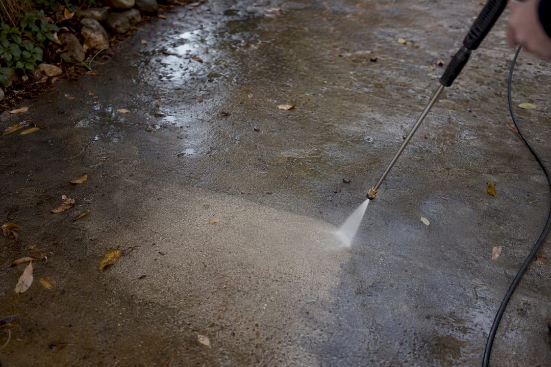 Pressure washer cleaning leaf stained concrete surface