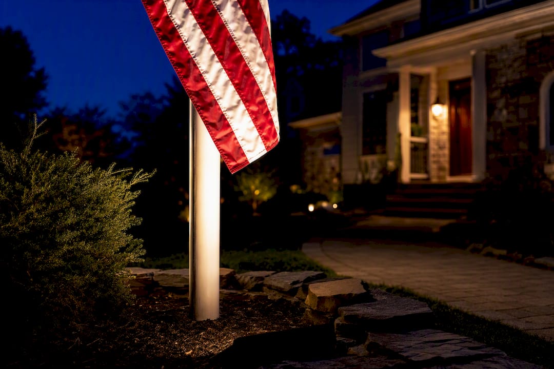 Flag illuminated beside a residential walkway
