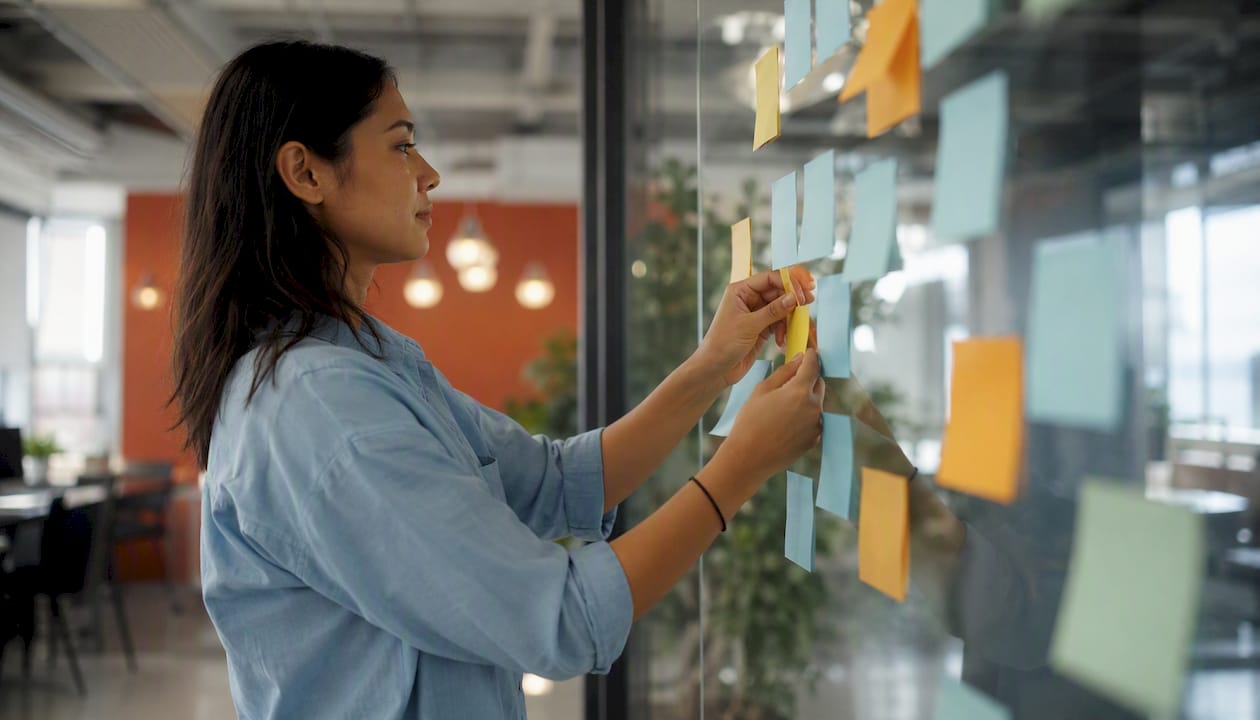 Hands placing sticky notes on board for sales planning