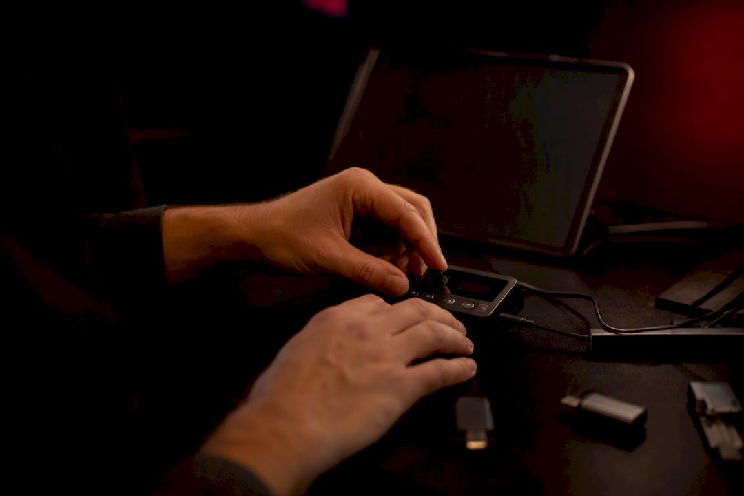 Hands holding a digital transcription device on dark desk