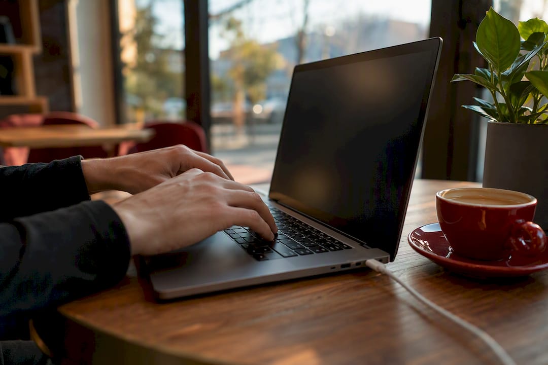Hands clicking Chrome extension near laptop edge