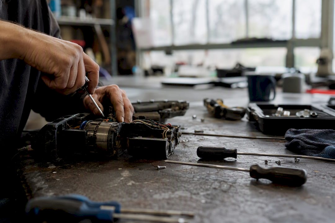 Hands repairing power tool in workshop