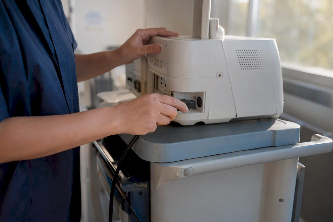 Hands plugging power cable into medical equipment