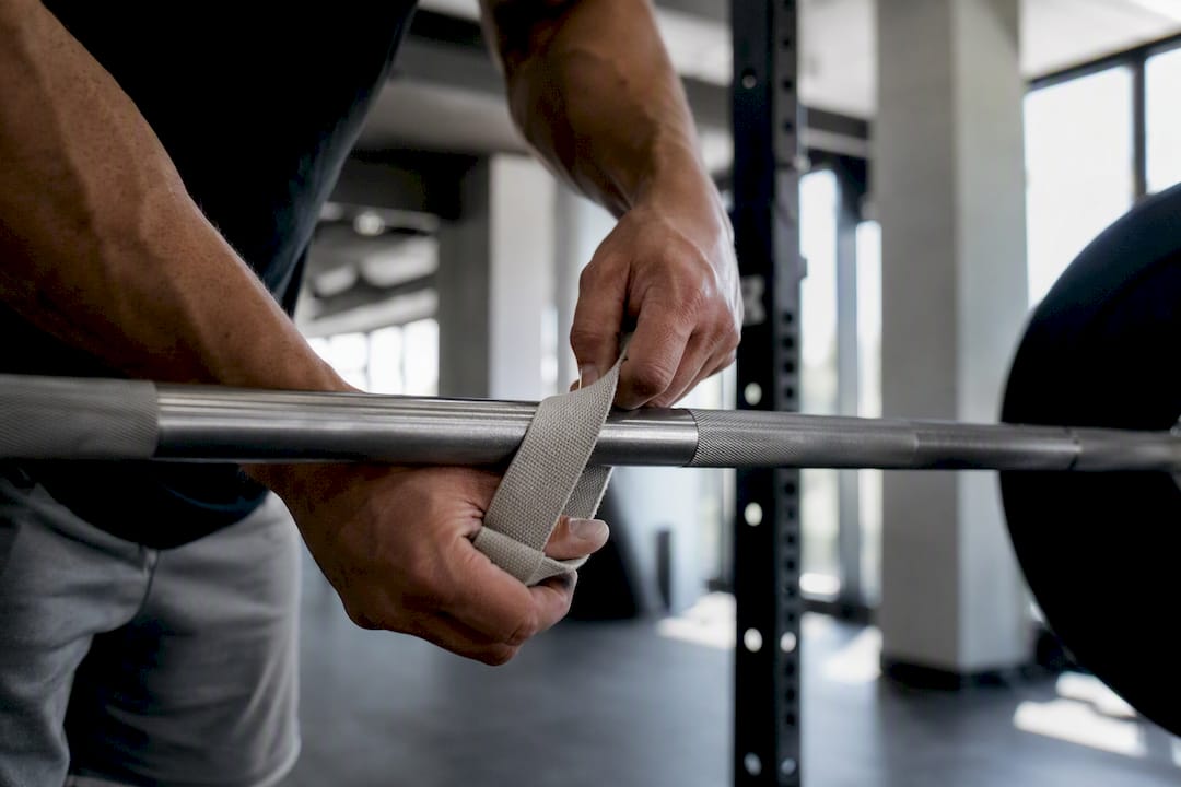 Hands wrapping lifting straps on barbell