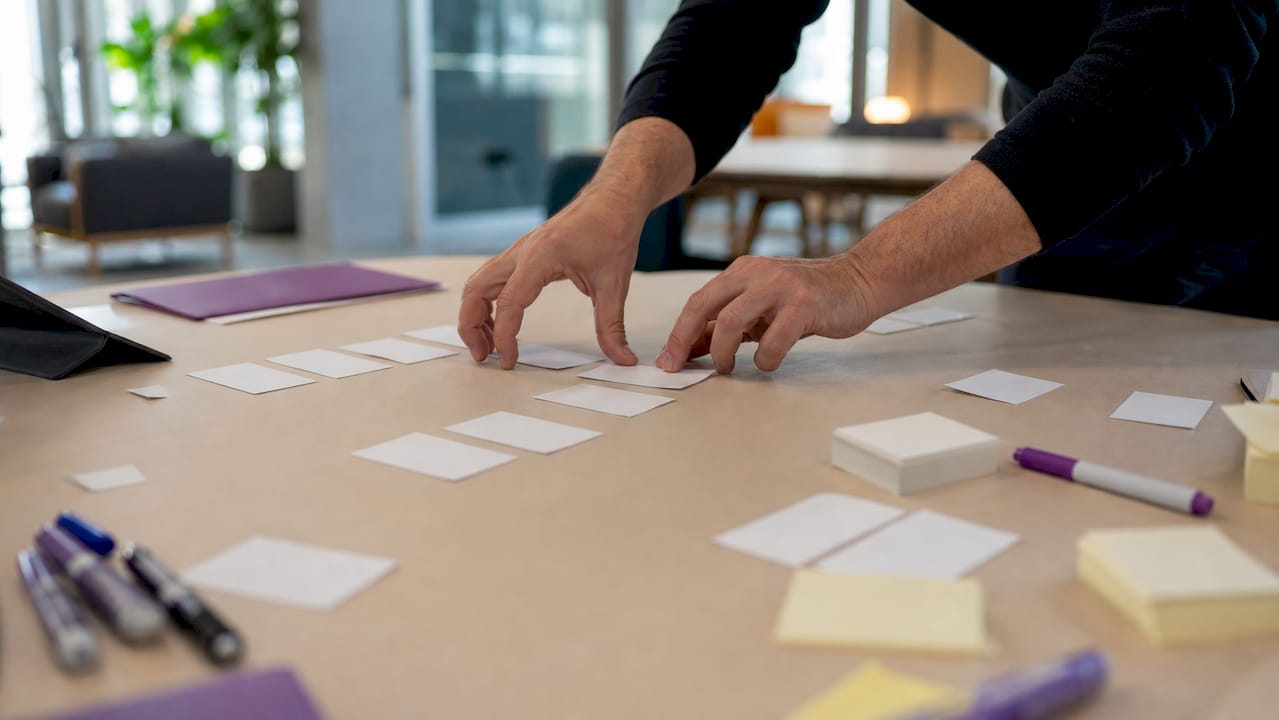 Hands arranging decision flow cards in workshop
