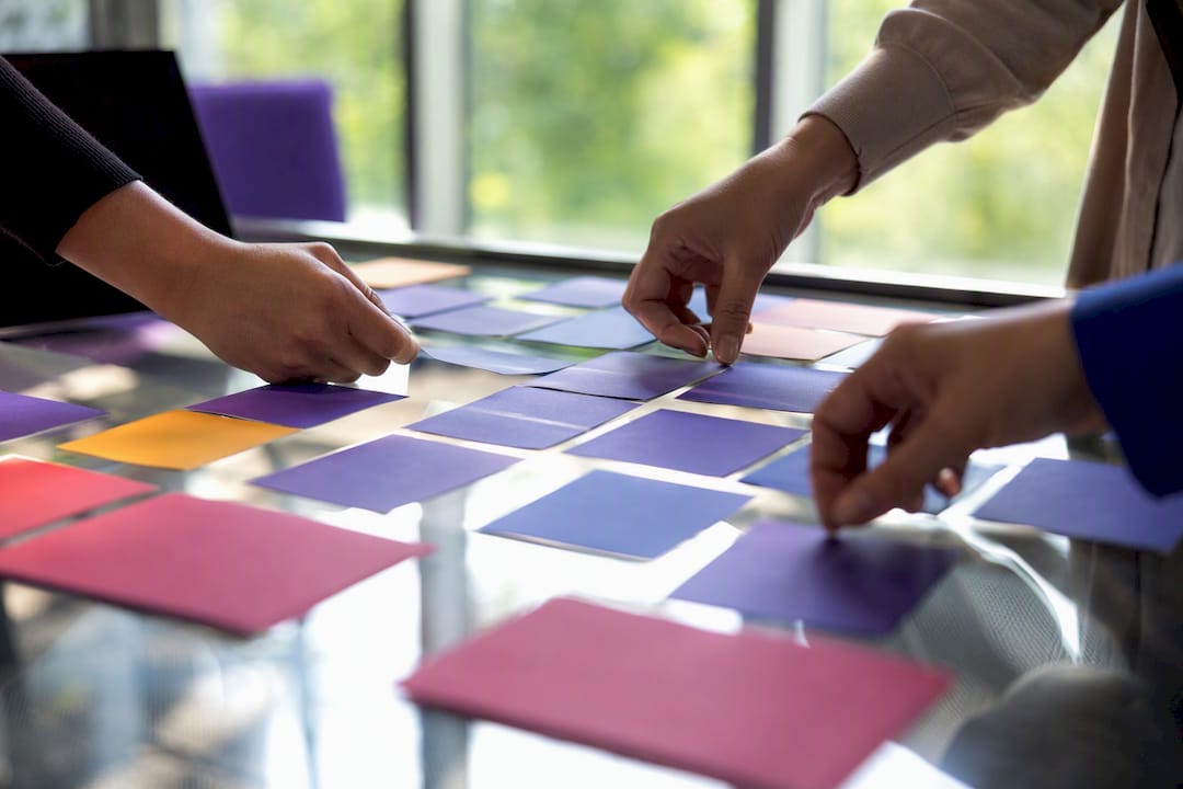Hands arranging capability strategy cards on table