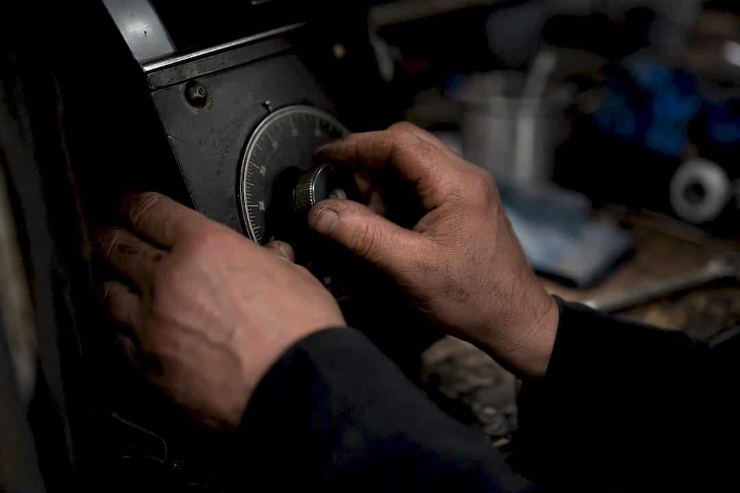 Hands adjusting an industrial instrument dial
