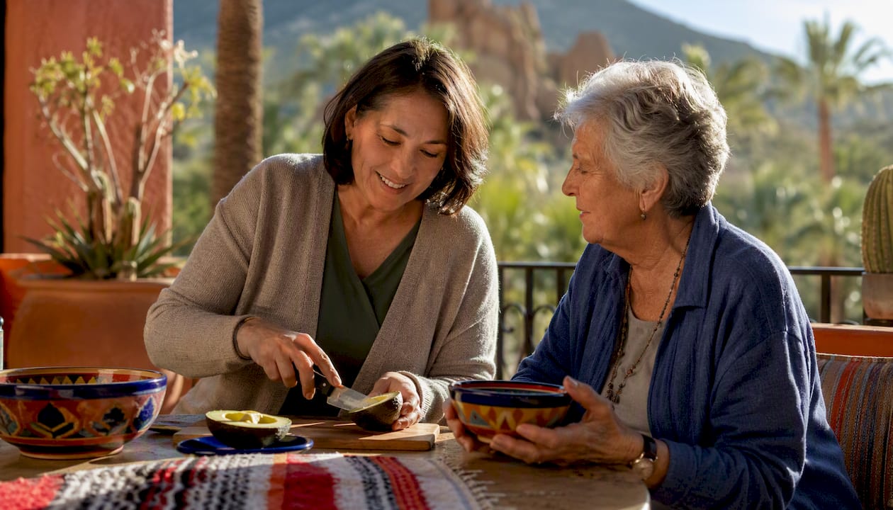 Caregiver and senior preparing snack outdoors