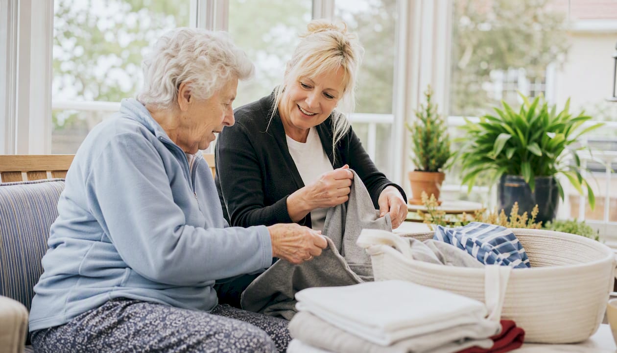 Senior companion folding laundry with elderly