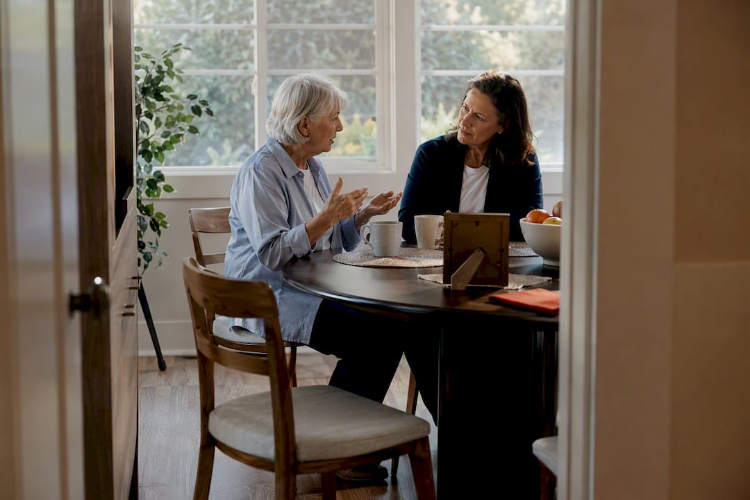 Older caregiver listening to senior at home